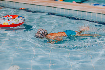 Happy young boy swim and dive underwater, kid breast stroke with fun in pool. Active healthy...