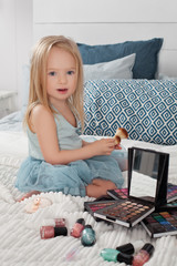 Pretty little girl and makeup cosmetics at home