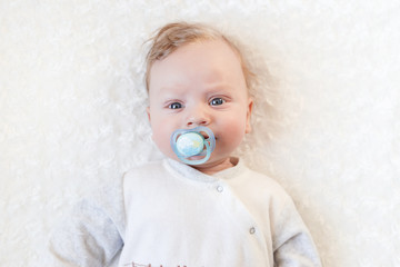 cute baby with pacifier on a white blanket