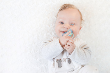cute baby with pacifier on a white blanket
