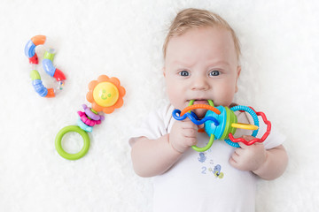 four-month-old boy chewing a rattle a white background