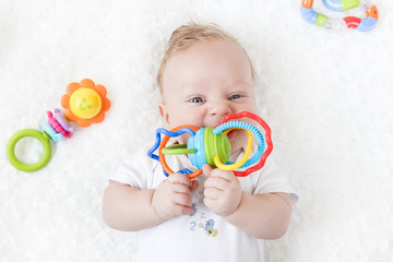 four-month-old boy chewing a rattle a white background