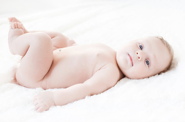 four month old boy with blue eyes lying on a white background