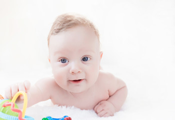 four month old white boy with blue eyes lying on his stomach on a white background
