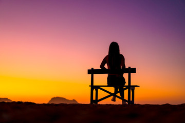 Fototapeta na wymiar Beautiful silhouette of one in a chair on the beach in a beautiful orange sunset