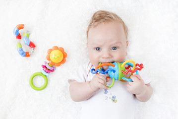 four-month-old boy chewing a rattle a white background