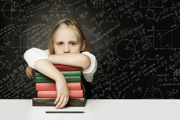 Tired child with books thinking on chalkboard with formulas