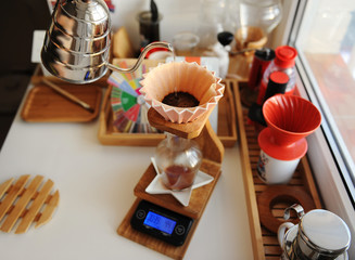 Pink ceramic origami dripper on wooden drip station on scale. Manual brewing still life