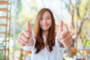 A happy beautiful asian woman making and showing thumbs up hand sign