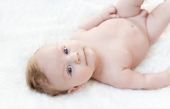 four month old white boy with blue eyes lying on a white background