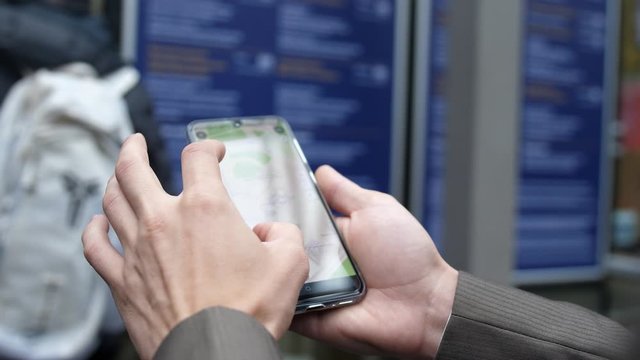 man uses a smartphone to observe ride sharing traffic patterns on an interactive map in a city.