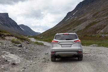 Obraz na płótnie Canvas Silver suv car standing on dirt road, driving through the mountains