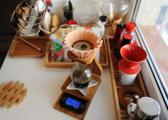 Pink ceramic origami dripper on wooden drip station on scale. Manual brewing still life