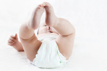 feet of a six months old baby wearing diapers lying on the bed
