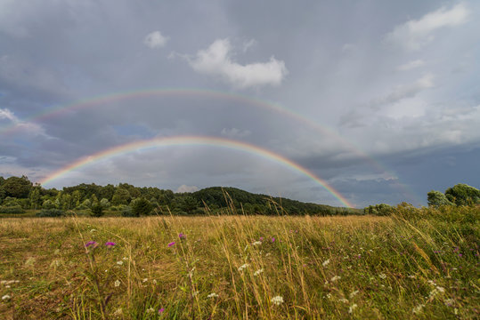 Beautiful summer landscape with a field and sky rainbow. Camping concept. Nature lovers concept.