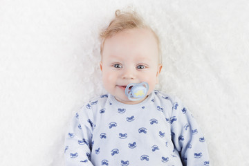 cute baby in blue pajamas with pacifier on a white background