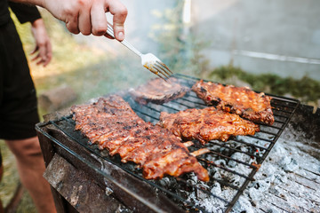 Cooking pork ribs on the grill, on an open fire, outdoors. Picnic and camping concept