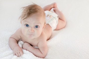 five-month-old blond boy with blue eyes lies on his stomach on a white background