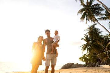 family happily walk along a tropical beach at sunset