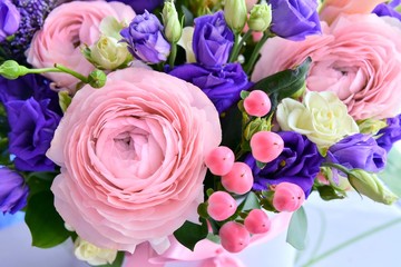 Fototapeta na wymiar Beautiful pink ranunculus flower with soft focus on tender petals and violet spring flowers on background. Beautiful bunch of spring flowers. Easter gift. Seasonal spring flowers