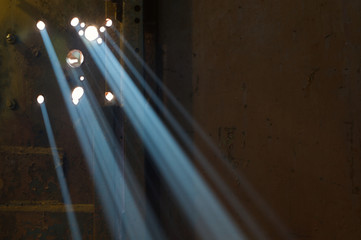 A sunbeam shines through the holes in the iron door. Horizontally. Targeted direct rays of light pass through the fog and create the effect of a multiple spotlight.