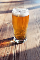 Glass of cold beer on the wooden table of a pub under natural afternoon light