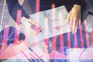 Multi exposure of hands making notes with forex chart huds. Stock market concept.