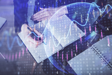 Forex chart hologram on hand taking notes background. Concept of analysis. Multi exposure