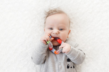 four-month-old boy chewing a rattle a white background