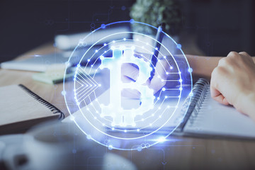 Cryptocurrency hologram, bitcoin, ico theme over hands taking notes background. Concept of blockchain. Multi exposure