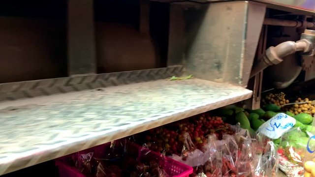 Railway train driving close to fruit and vegetable on ground in Maeklong Railway Market
