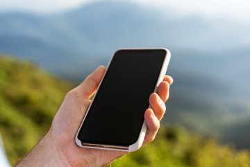 guy holding a phone in the mountains at sunset