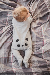 little boy in a panda costume lies on the bed. ass baby