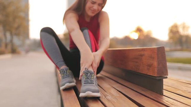 Young sportswoman having pain / injury during exercise and jogging in the park.