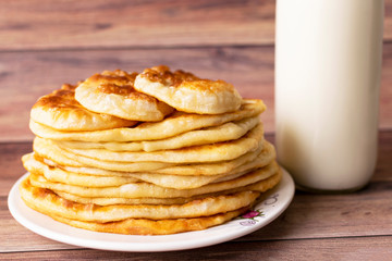 Healthy rustic food. Milk in a bottle, a glass and hot cakes for breakfast. Wheat, corn flour cakes. Wood background.
