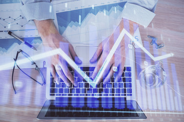 Double exposure of market chart with man working on computer on background. Concept of financial...