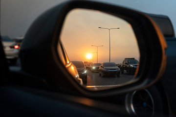 Sunset in a rear view mirror with traffic jams on expressways. sunset car driving scene.