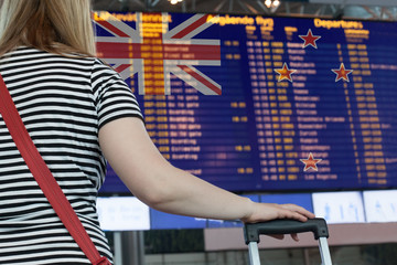 Woman looks at the scoreboard at the airport. Select a country New Zealand for travel or migration.