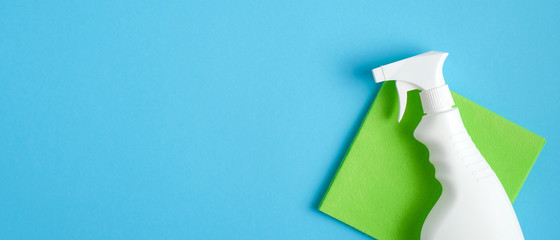 Blank cleaning spray bottle and green rag on blue background. Flat lay, top view. House cleaning...