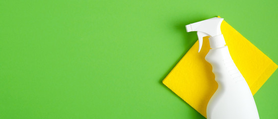 Blank cleaning spray bottle and yellow rag on yellow background. Flat lay, top view. House cleaning...