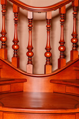 Element of a wooden staircase with carved balusters and mahogany railings.