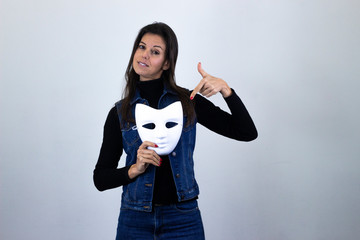 Portrait of fashionable middle age woman modelwhite mask pointing with fore finger the object,...