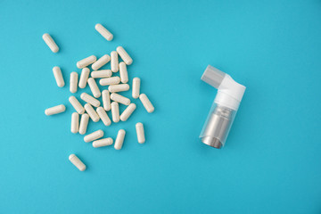 Assorted pharmaceutical medicine capsules with asthma inhaler on blue background.Medical, pharmacy...