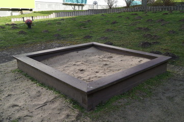 Wooden sandpit in the garden with toys. The world of children.