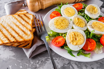salad with boiled chicken eggs and cherry tomatoes on a stone background