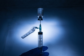Vial de medicamento con aguja y jeringa preparándose para administrar vacuna