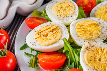 salad with boiled chicken eggs and cherry tomatoes on a wooden rustic background