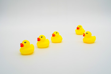 Five mini yellow rubber ducks in a row. One duck making their wa