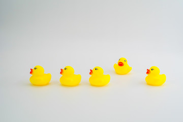 Five mini yellow rubber ducks in a row. One duck making their wa