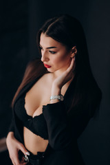 Naklejka premium a young girl with dark hair, brown eyes and bright red lips poses in a Studio in a black pantsuit